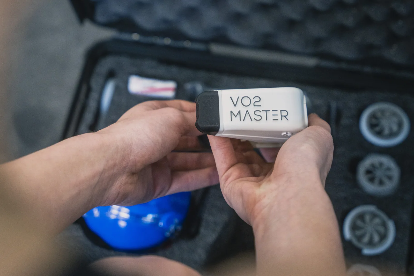The VO2 Master analyser held above its case alongside the mask and filters