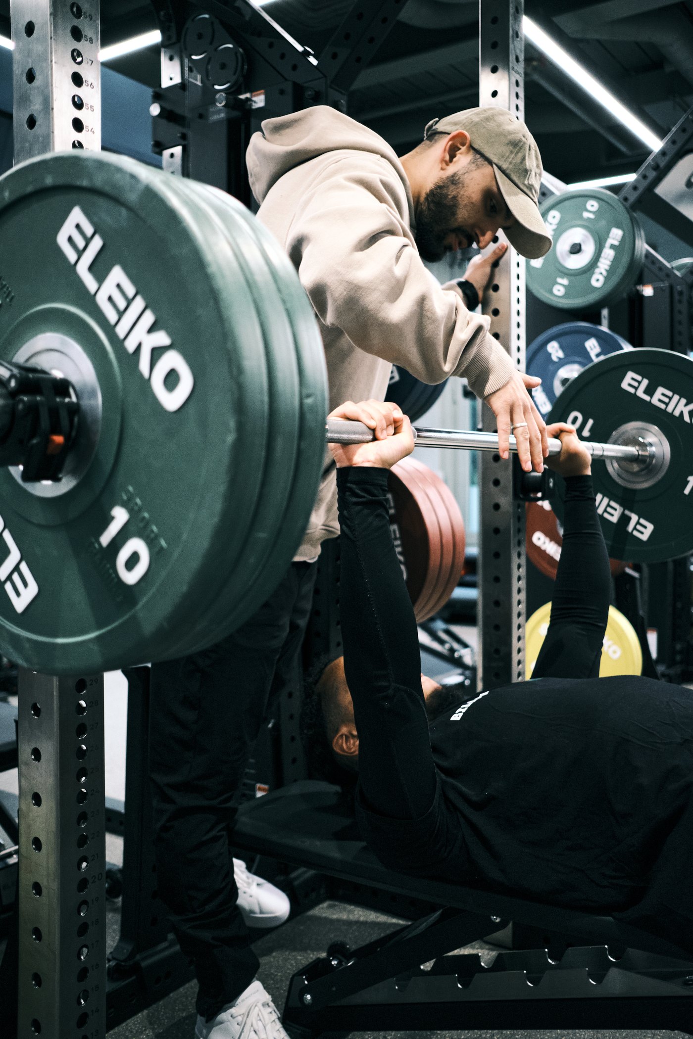 Coach spotting a client through a barbell bench press